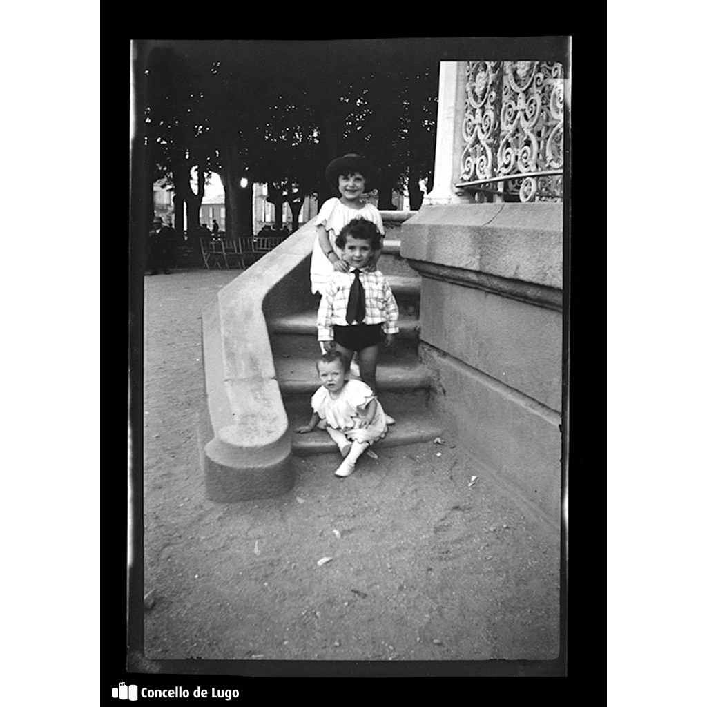 Retrato de tres nenos xogando no quiosco da Praza Maior