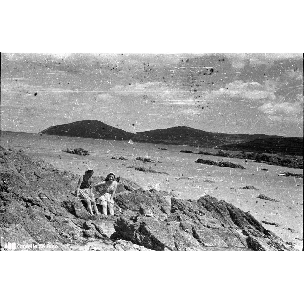 Retrato de dúas mulleres sentadas nunhas rochas na praia